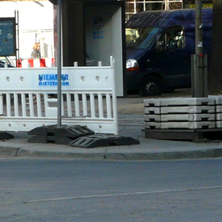 Absperrgitter und Aufstellfuß für ein Schild behindern die Fußgänger an einem Übergang.